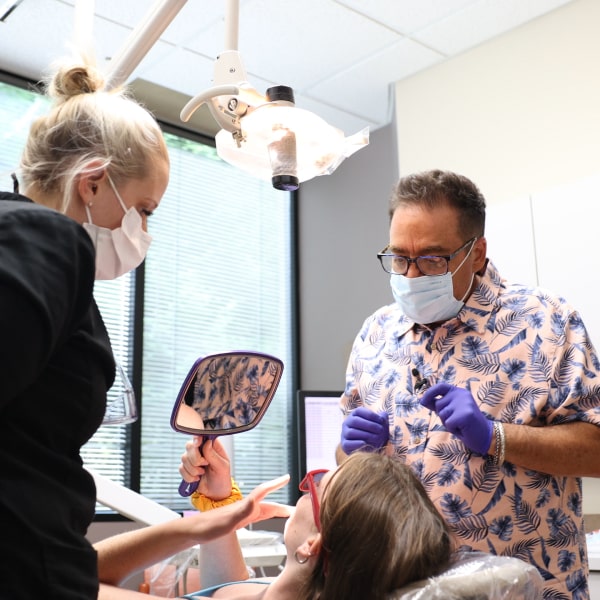 Dr. Ron Sherman with his dental assistant and satisfied patient in a dental chair