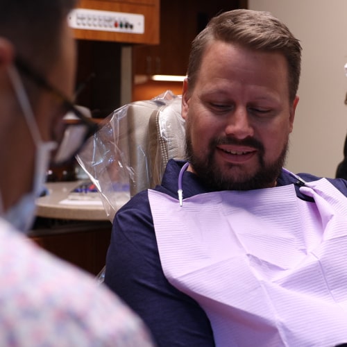 A man in a dental chair with a dentist behind him
